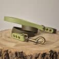 A Custom Two Colour 1.2m Lead in green and brown with brass fittings is coiled on a round wooden surface against a neutral background, combining style and function for everyday walks.