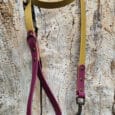 A yellow and maroon dog lead with metal fittings is laid out on a textured, weathered wooden surface.