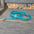 A Single colour Multi-Way lead in Cerulean Blue, made from synthetic material, is coiled on a weathered outdoor wooden bench with tree roots and dry pine needles in the background.