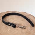 A black textured Super-grip Biothane Training Tab / Obedience Lead 51cm with a metal clasp, shown on a round wooden surface with visible tree rings.