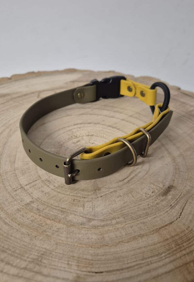 The Quick-Snap Bungee Collar features olive green and yellow straps, metal buckles, and a black plastic clasp, shown on a round wooden surface.