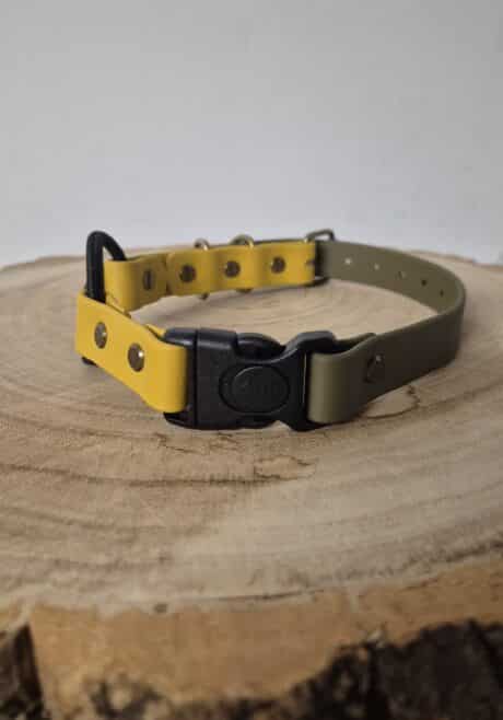 The Quick-Snap Bungee Collar, featuring yellow and olive green colours with a black quick-snap buckle, rests on a round wooden surface displaying visible tree rings.
