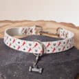 The Custom Snap Tag - Slip Collar is a white, quick-snap customisable dog collar with red horse, black star, and horseshoe patterns, plus a small silver bone charm. Displayed on grey stone with a light background.