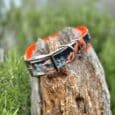 Printed double layer hound collar in vibrant orange and black dragon design displayed on weathered wood.