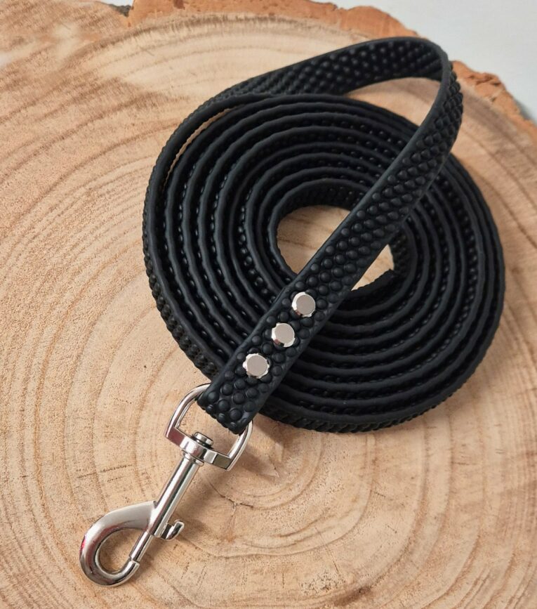 Black super grip BioThane dog lead coiled on wood with textured grip handle and metal clip attachment.