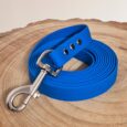 Bright blue waterproof longline coiled on natural wood, featuring silver hardware and textured BioThane handle with three eyelets.