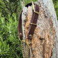 Brown BioThane adjustable martingale half-check collar with brass hardware and chain attachment, displayed on weathered wood post.