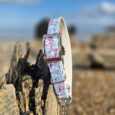 Blue floral printed adjustable martingale half-check collar with stainless steel hardware, displayed on weathered wood outdoors.