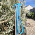 Bright blue polka dot double-ended training lead with metal clasps, displayed on wooden post against blooming garden.