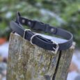 Black BioThane quick-snap bungee collar strap with nickel hardware, displayed on weathered wood.