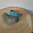 Bright blue and orange BioThane centre ring dog collar with nickel hardware, displayed on natural wood.
