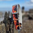 Flames-printed adjustable martingale half-check collar with stainless steel hardware, displayed on weathered wood against coastal backdrop.