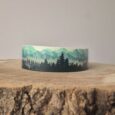 Forest print extra wide waterproof BioThane collar displayed on textured wood surface, showcasing layered mountain and tree design in green and black tones.