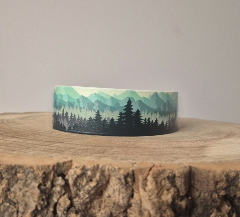 Forest print extra wide waterproof BioThane collar displayed on textured wood surface, showcasing layered mountain and tree design in green and black tones.