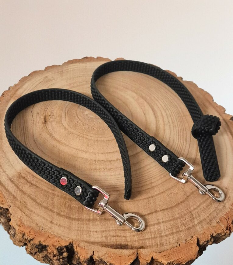 Two black Super-grip Waterproof Training Tab Obedience Leads with textured grip handles and nickel hardware, displayed on natural wood.