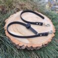 Two black Super-Grip Waterproof Training Tab Obedience Leads displayed on a wood slice, featuring textured grip handles and nickel hardware.