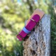 Vibrant magenta and blue custom tapered hound collar displayed on weathered wood post outdoors.