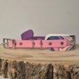 Pink waterproof BioThane hound collar with patterned design, metal D-rings, and buckle hardware displayed on wooden surface.