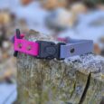 Vibrant pink and lavender quick-snap bungee collar strap with lockable buckle, displayed on weathered wood.
