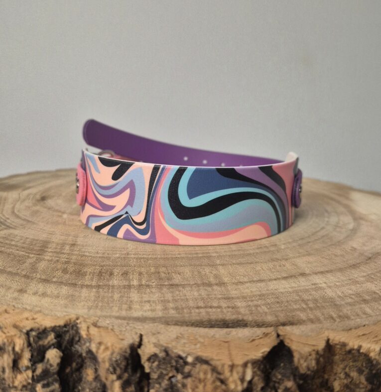 Printed tapered hound collar in vibrant abstract swirl pattern with purple BioThane backing, displayed on wooden surface.