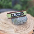 Personalised BioThane hound collar with TEN-K nameplate in sage green and burgundy, displayed on stone.