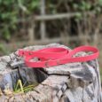 Bright pink 1.2m BioThane dog lead coiled on weathered wood, showcasing durable synthetic material and metal hardware.