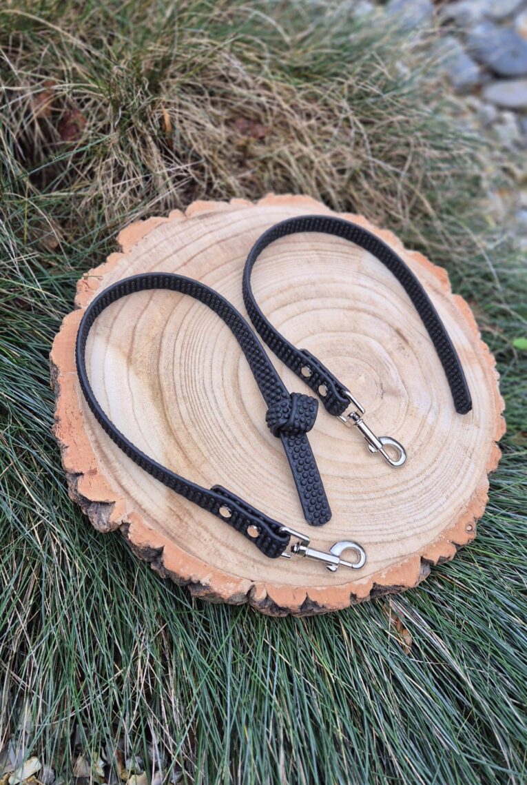 Black super-grip waterproof training tab obedience lead coiled on wood, displaying textured grip surface and nickel hardware.