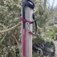 Waterproof BioThane double-ended lead in burgundy and black with traffic handle, displayed on wooden post.