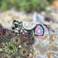Colourful extra wide printed BioThane collar displayed on succulent plants, featuring vibrant floral and geometric patterns on black.