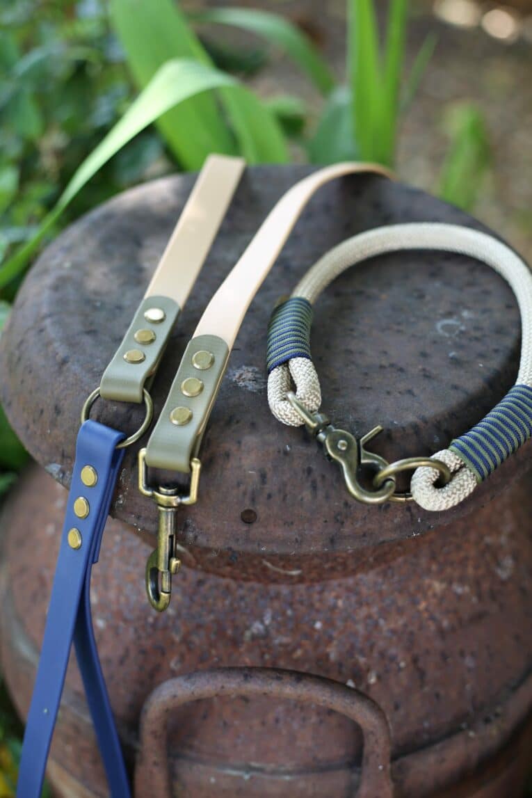 Three handmade dog leads in beige, navy and olive, featuring antique brass hardware and paracord detailing from the Aubreys x Lutchfords collaboration.