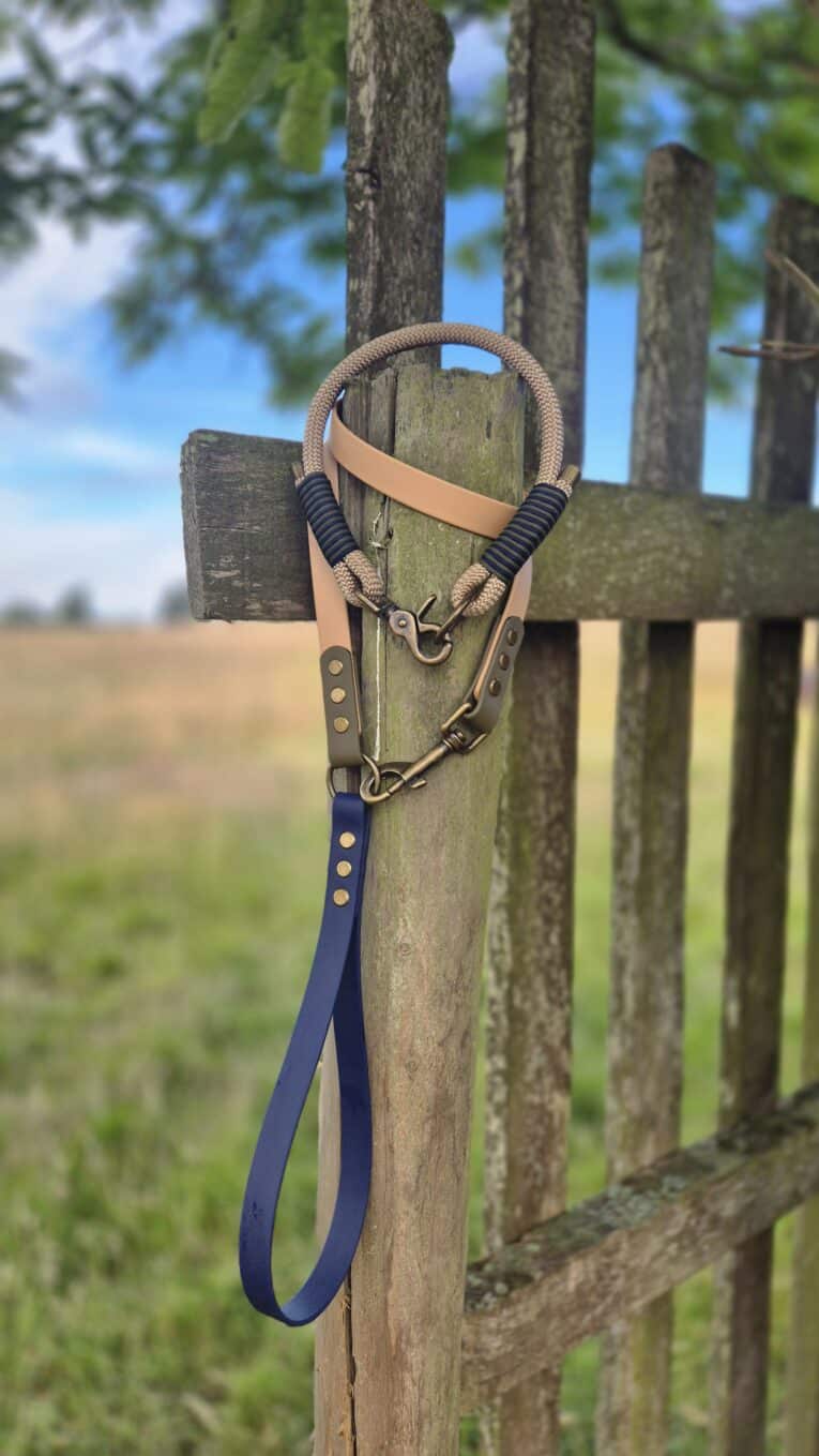 Aubreys x Lutchfords paracord collar and BioThane lead in signature beige, navy and olive, displayed on rustic fence.