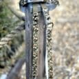Camouflage printed BioThane lead with stainless steel hardware and D-ring, displayed on weathered wood post.