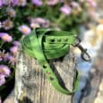 Bright green waterproof longline with metal hardware coiled on weathered wood, surrounded by purple flowers.