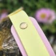 Custom double layer hound collar in pale yellow and pink with stainless steel hardware, displayed on weathered wood with flowers.